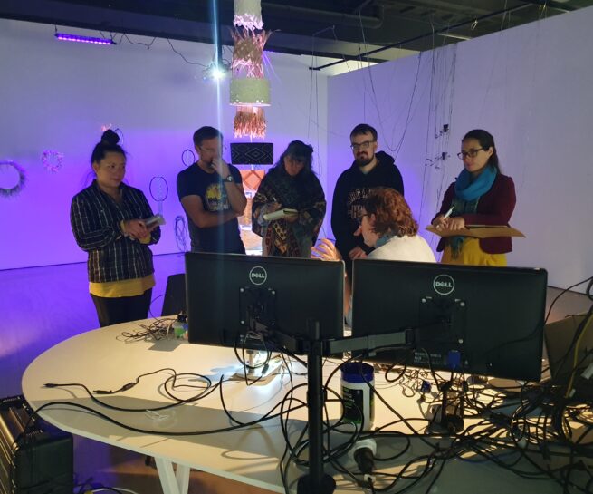 Training Courses and Workshops exemplified by people standing around talking in front of projections