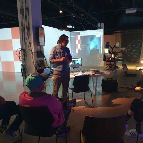 20230614_111256 Creative Technology Training in Action in front of a projection mapped background and students on chairs in front